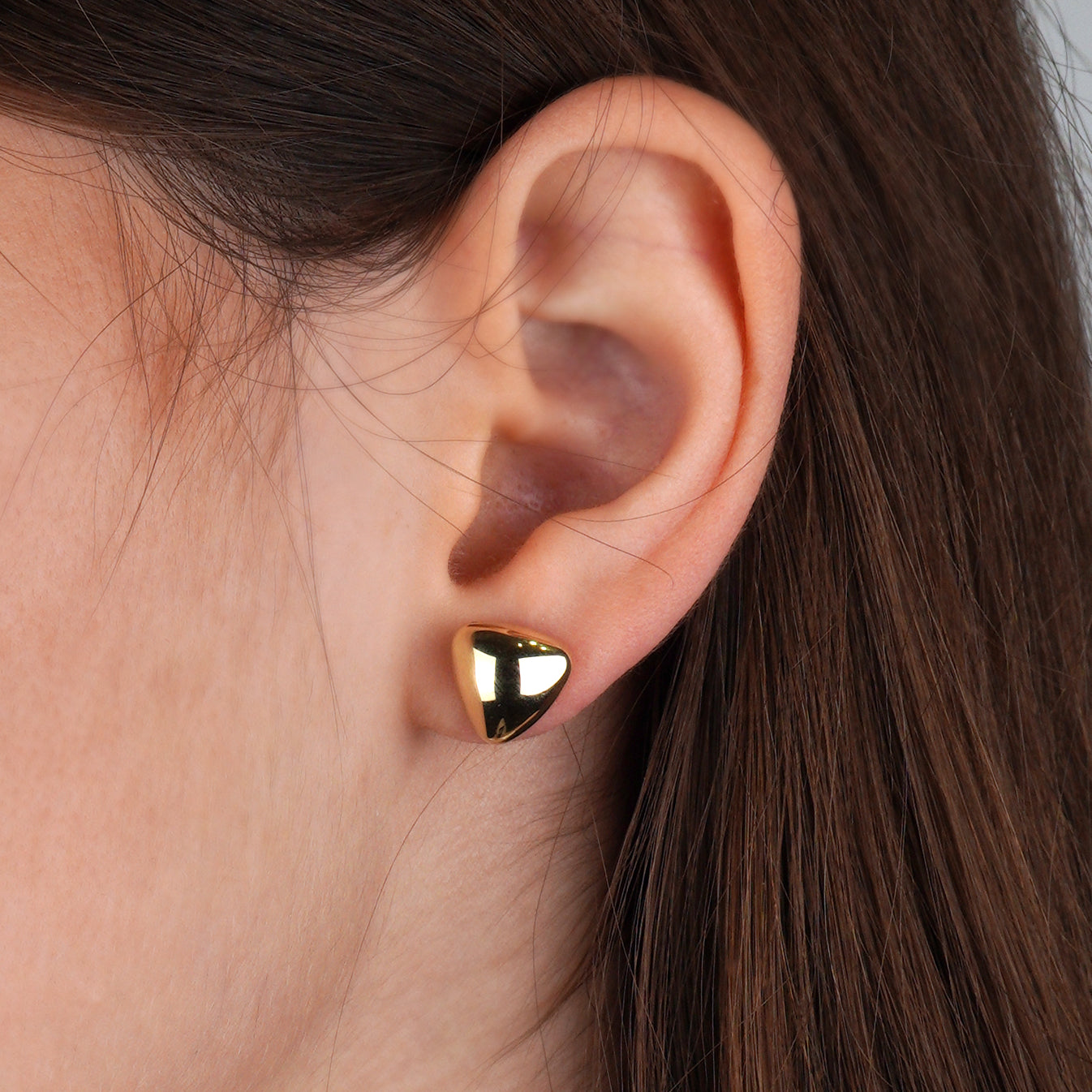 Małe złote kolczyki w kształcie zaokrąglonego trójkąta, idealne na co dzień