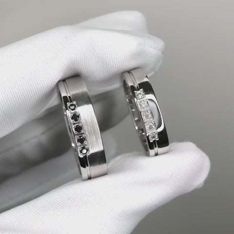Jego i jej obrączki z czarnymi i białymi diamentami. Zestaw złotych obrączek ślubnych. Diamentowe obrączki ślubne. Obrączki z białego złota z diamentami.