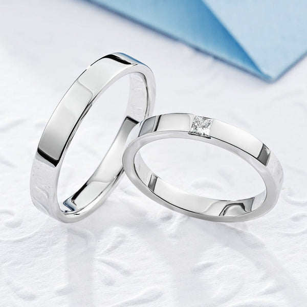 Zwykłe złote obrączki ślubne z diamentem o szlifie princessa. Zestaw obrączek ślubnych dla pary. Proste obrączki ślubne. Obrączki z białego złota z diamentem. Diamentowa obrączka o szlifie princessa. 